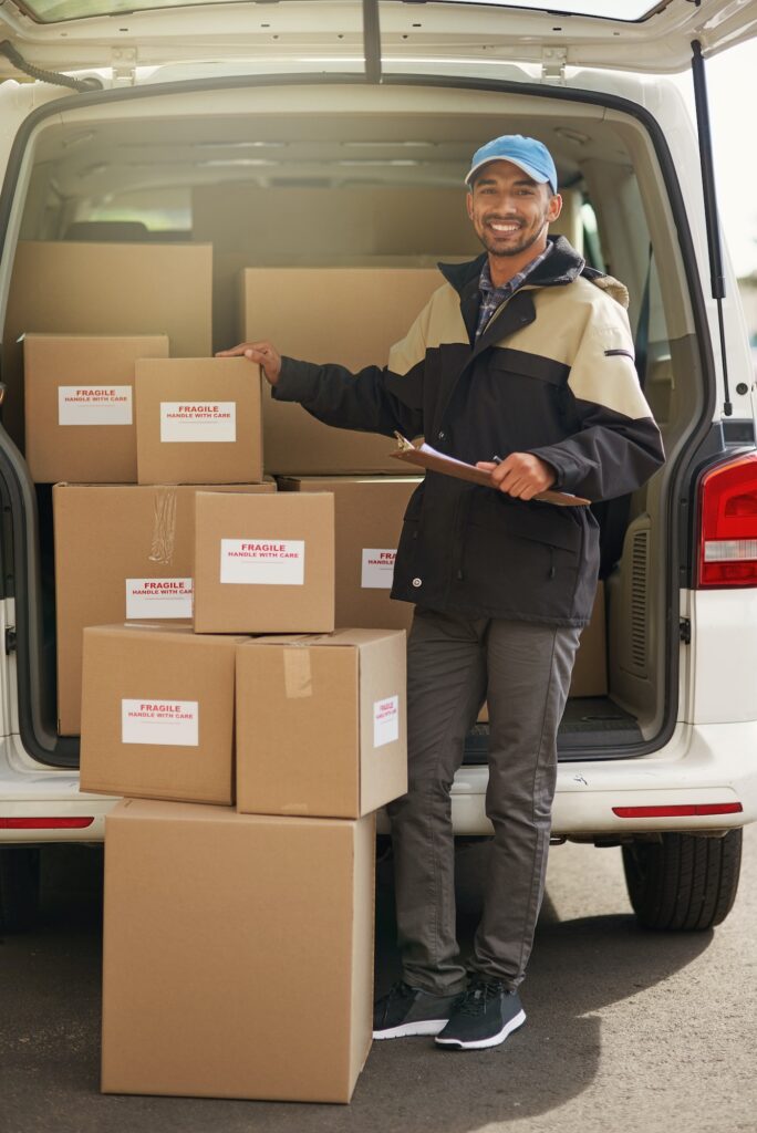 Portrait of a smiling delivery man loading boxes into his truck